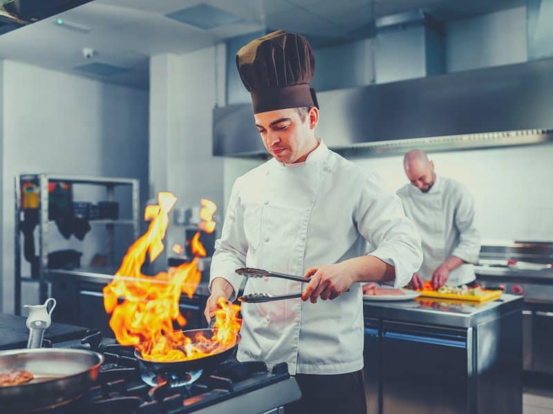 chef preparing food in a kitchen using a natural gas stove