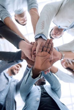 Diverse team of professionals stacking hands for teamwork and collaboration in a modern office.
